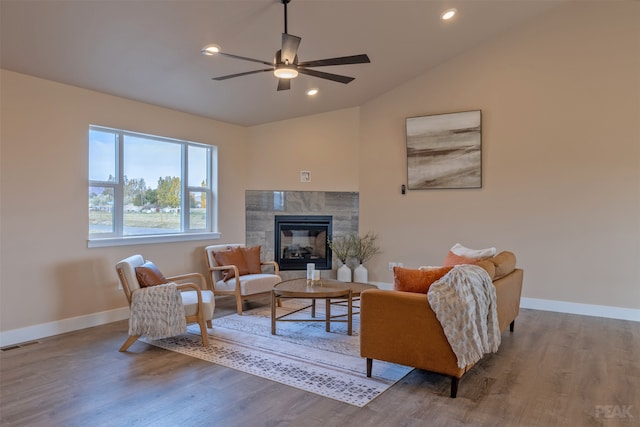 living room featuring lofted ceiling, a tiled fireplace, wood-type flooring, and ceiling fan