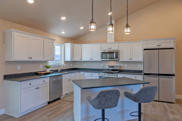 kitchen with white cabinets, appliances with stainless steel finishes, vaulted ceiling, light hardwood / wood-style flooring, and sink