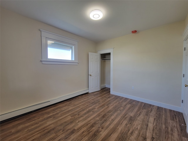 unfurnished bedroom featuring dark wood-type flooring, a closet, and a baseboard radiator