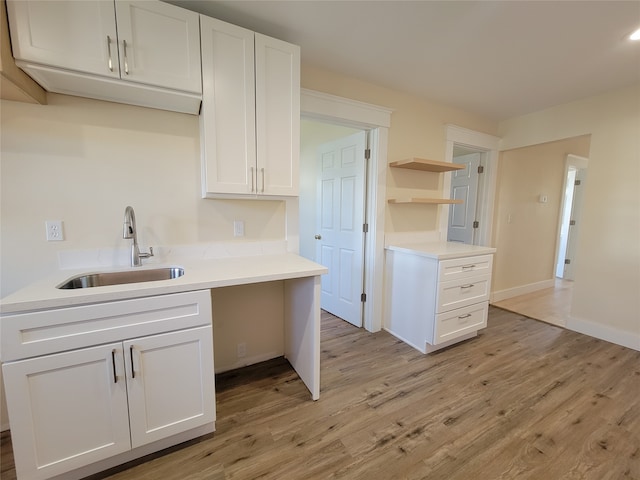 kitchen featuring white cabinets, light wood-type flooring, and sink