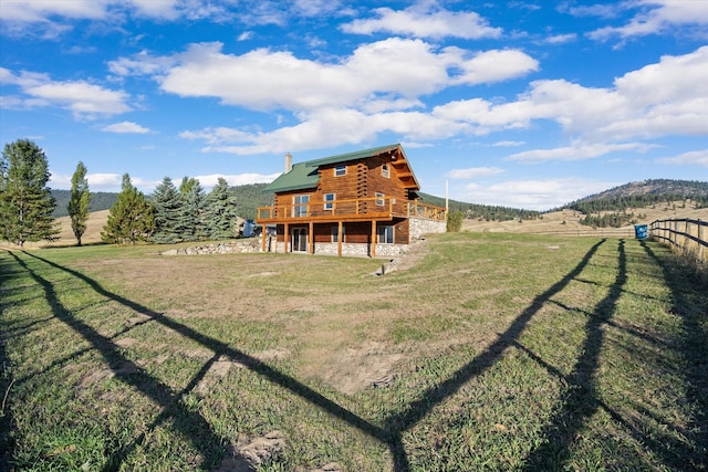 back of property with a deck with mountain view, a rural view, and a yard