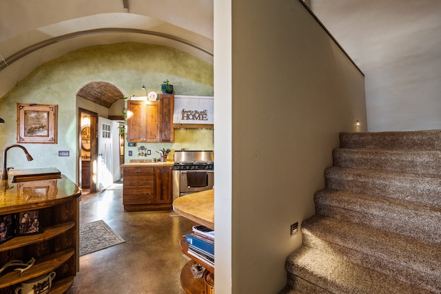 stairway featuring lofted ceiling, sink, and concrete floors