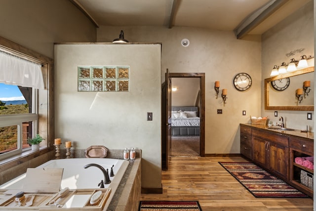 bathroom with beam ceiling, hardwood / wood-style flooring, vanity, and a bathing tub