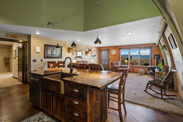 kitchen featuring a center island with sink, sink, decorative light fixtures, and stainless steel dishwasher