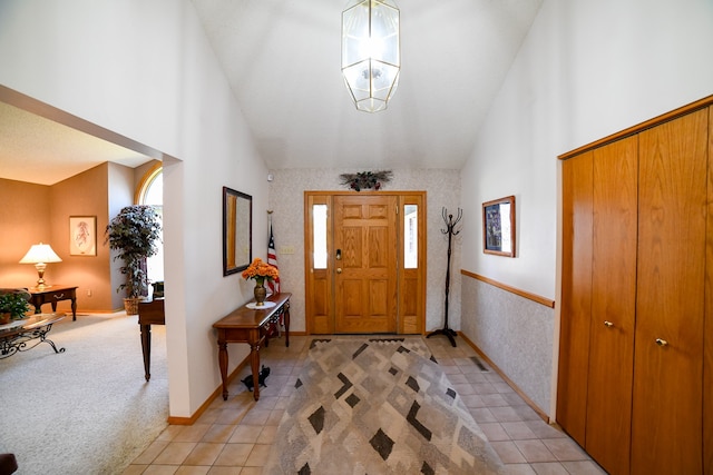 entrance foyer featuring a chandelier, light carpet, and high vaulted ceiling