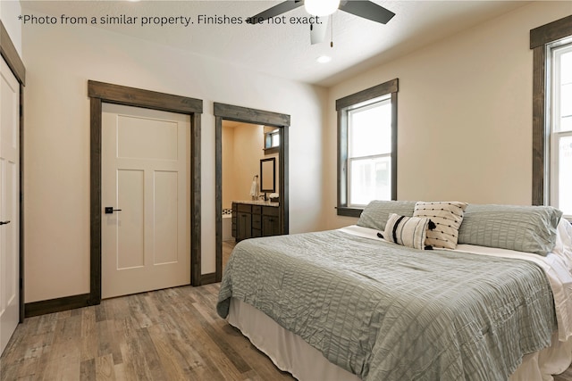 bedroom featuring connected bathroom, multiple windows, hardwood / wood-style flooring, and ceiling fan