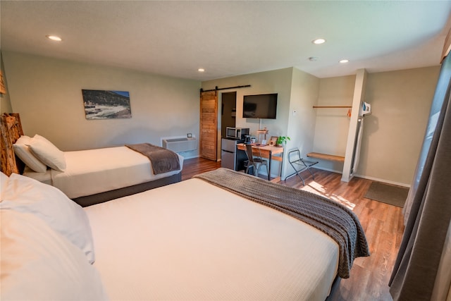 bedroom with a barn door and light hardwood / wood-style floors