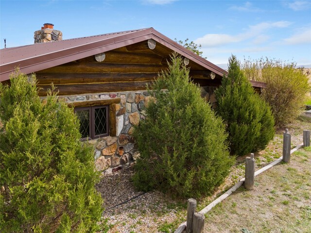 view of side of property featuring stone siding and a chimney