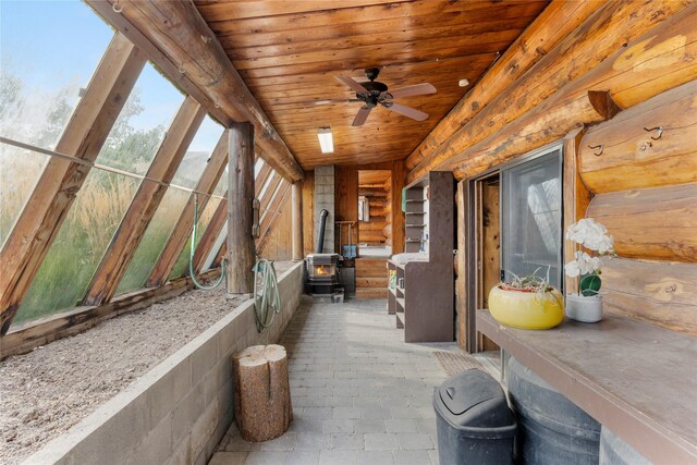 sunroom / solarium featuring a wood stove and a healthy amount of sunlight