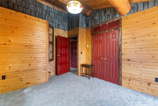 carpeted bedroom featuring wood ceiling, wood walls, and a closet