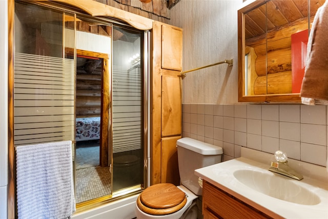 bathroom featuring tile walls, tasteful backsplash, vanity, toilet, and an enclosed shower