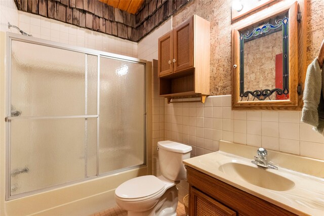 full bathroom featuring toilet, tile walls, backsplash, combined bath / shower with glass door, and vanity