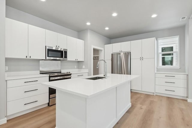 kitchen with sink, white cabinetry, stainless steel appliances, and a kitchen island with sink