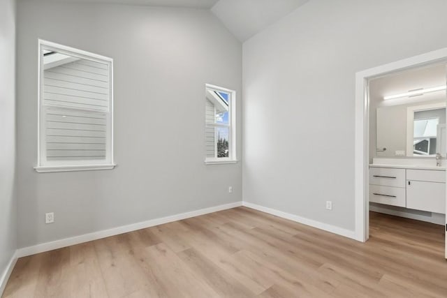 304 Trailview Way, Whitefish, MT 59937 - unfurnished bedroom with lofted ceiling, light wood-type flooring, and ensuite bath