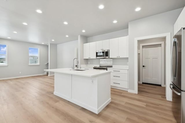 304 Trailview Way, Whitefish, MT 59937 - kitchen with appliances with stainless steel finishes, an island with sink, light wood finished floors, white cabinets, and light countertops