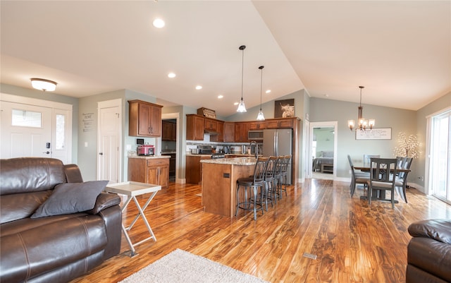 kitchen featuring pendant lighting, a center island, a breakfast bar area, vaulted ceiling, and light stone countertops