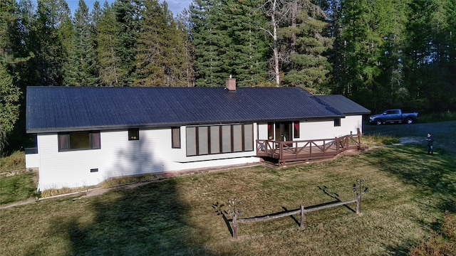 rear view of property with a chimney, metal roof, crawl space, a yard, and a wooden deck