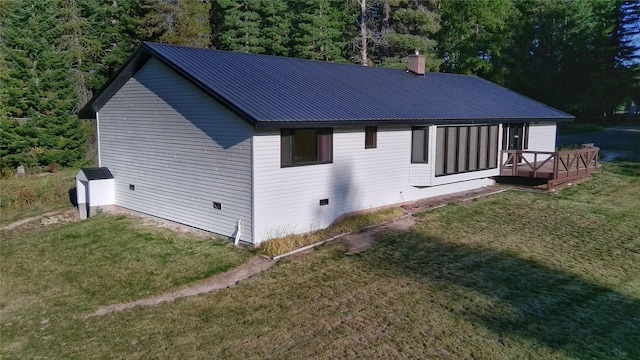 view of side of home featuring a lawn, a wooden deck, a chimney, and metal roof