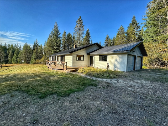 rear view of house featuring metal roof, a yard, and a wooden deck