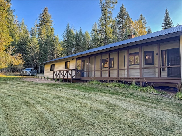 rear view of property with a yard, a chimney, and metal roof