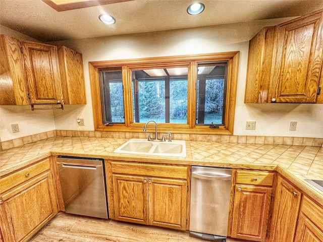 kitchen with dishwasher, tile countertops, brown cabinetry, and a sink