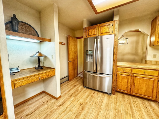 kitchen with a baseboard radiator, light wood-style floors, light countertops, stainless steel refrigerator with ice dispenser, and brown cabinetry