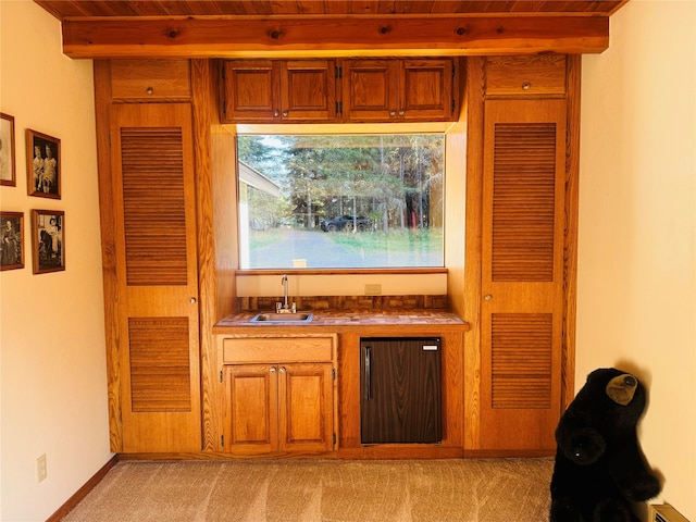 bar featuring black fridge, light colored carpet, a sink, and beamed ceiling