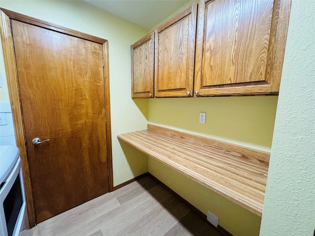 interior space featuring light wood finished floors, washer and dryer, cabinet space, and baseboards