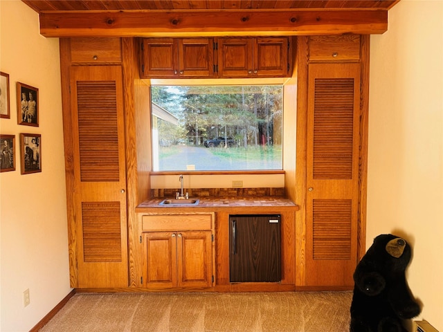 bar featuring refrigerator, a sink, indoor wet bar, light carpet, and beamed ceiling