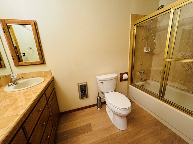 bathroom featuring toilet, shower / bath combination with glass door, wood finished floors, vanity, and baseboards