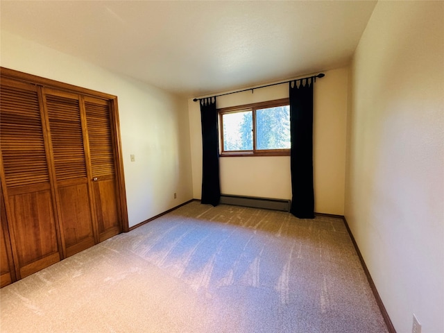 unfurnished bedroom featuring a baseboard heating unit, a closet, light colored carpet, and baseboards