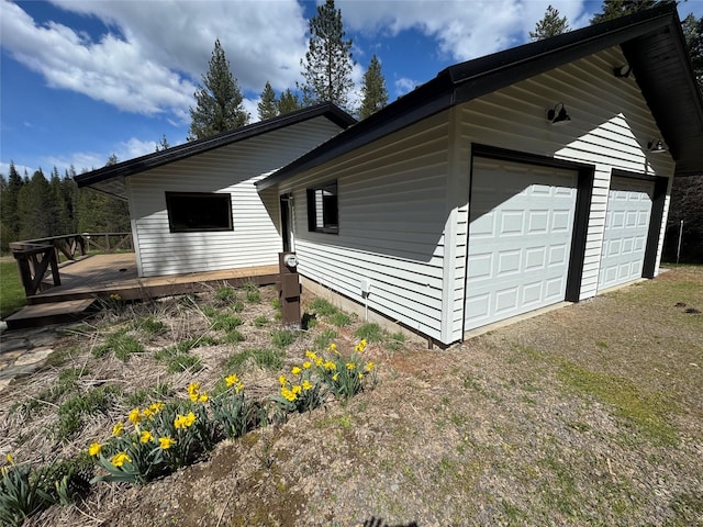 view of home's exterior with a wooden deck, driveway, and a garage