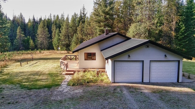 detached garage featuring a forest view and gravel driveway
