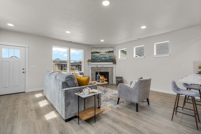 5803 Horn Rd, Missoula, MT 59808 - living area with light wood-style flooring, a textured ceiling, baseboards, and a warm lit fireplace