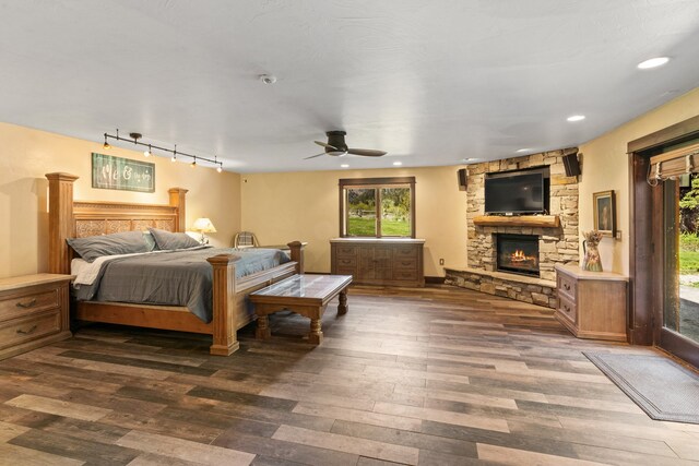 bedroom with rail lighting, a fireplace, dark hardwood / wood-style flooring, and ceiling fan