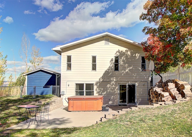 back of property featuring a lawn, a hot tub, and a patio area