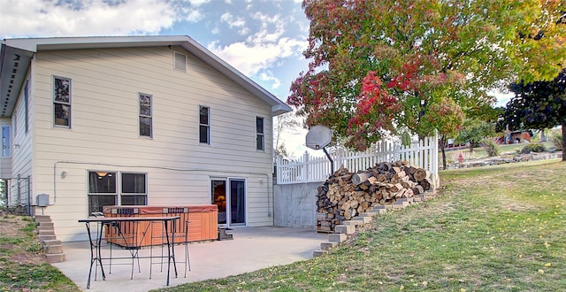 rear view of house with a patio, a hot tub, and a yard