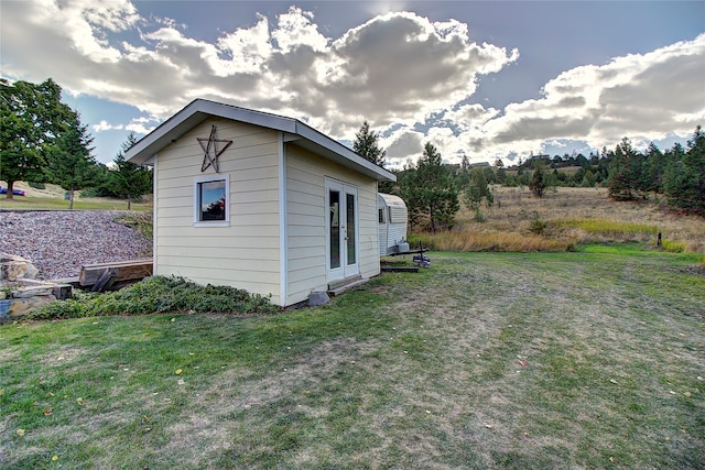 view of property exterior with a lawn and an outbuilding