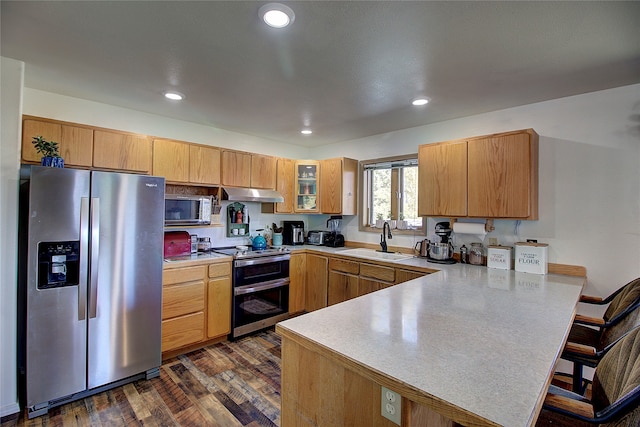 kitchen with sink, kitchen peninsula, appliances with stainless steel finishes, dark hardwood / wood-style floors, and a kitchen bar