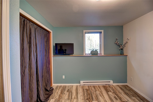 laundry room with hardwood / wood-style flooring, baseboard heating, and a textured ceiling