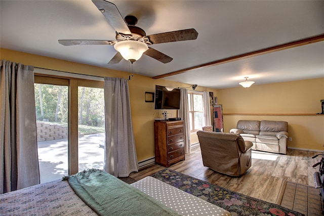 bedroom with light hardwood / wood-style floors, multiple windows, baseboard heating, and ceiling fan