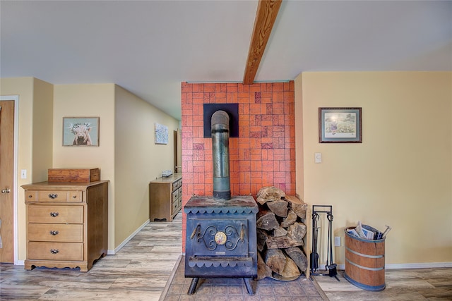 room details with beam ceiling, a wood stove, and hardwood / wood-style flooring