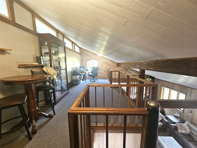 living room with wooden walls, lofted ceiling, and carpet