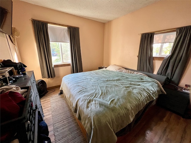 bedroom with multiple windows, wood-type flooring, and a textured ceiling