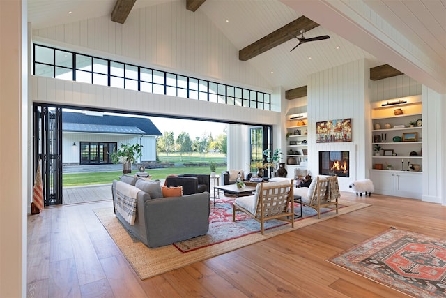 living room with high vaulted ceiling, beam ceiling, light hardwood / wood-style floors, and built in features