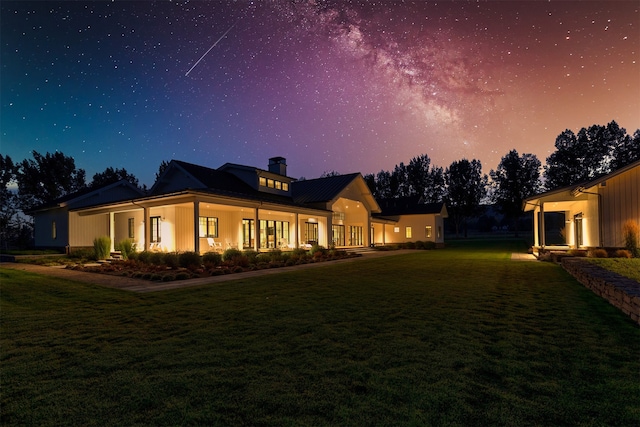 back house at dusk featuring a lawn