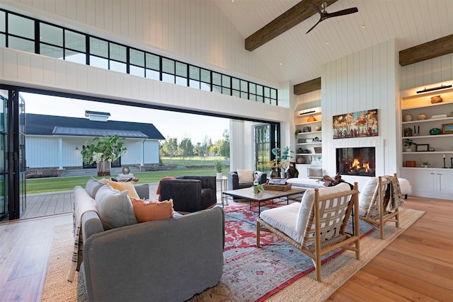 living room featuring high vaulted ceiling, built in shelves, beam ceiling, and light hardwood / wood-style floors