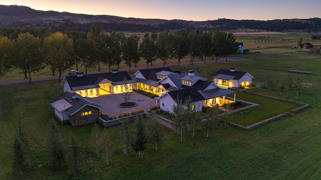 aerial view at dusk featuring a mountain view and a rural view