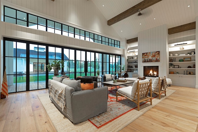 living room with light hardwood / wood-style floors, high vaulted ceiling, a fireplace, beam ceiling, and built in features