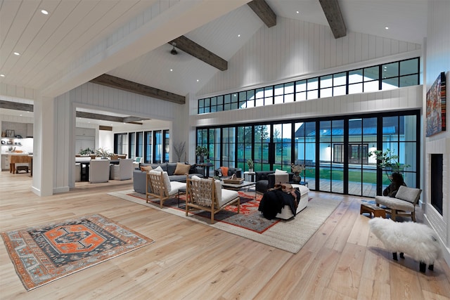 living room featuring high vaulted ceiling, light wood-type flooring, and beamed ceiling